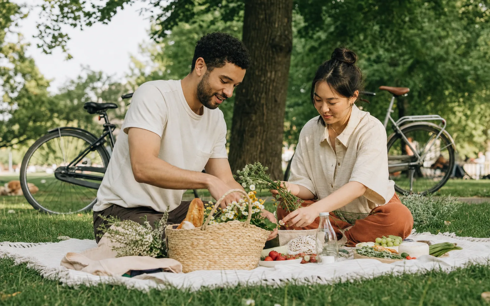 Ein Paar bereitet gemeinsam ein Picknick in einem grünen Stadtpark vor.